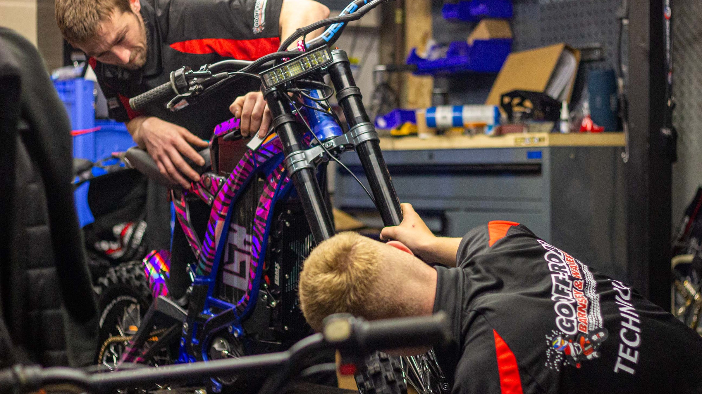 Two mechanics working on a bicycle in a workshop.